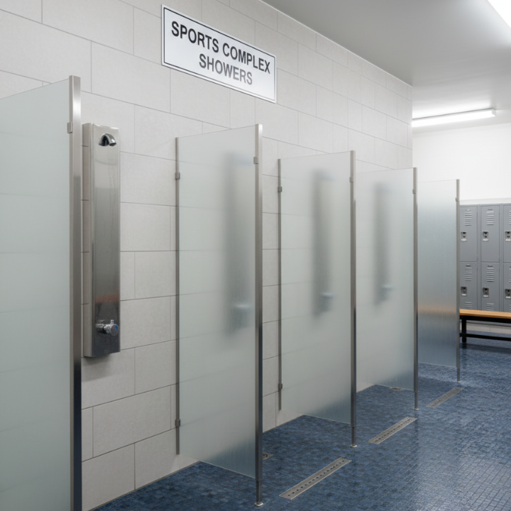 Push button Shower stalls in a sports complex with a sign above.